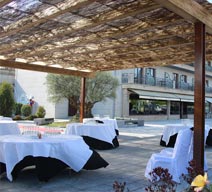 Mesas para cocltail de bienvenida bajo pérgola en Hotel Alfonso I